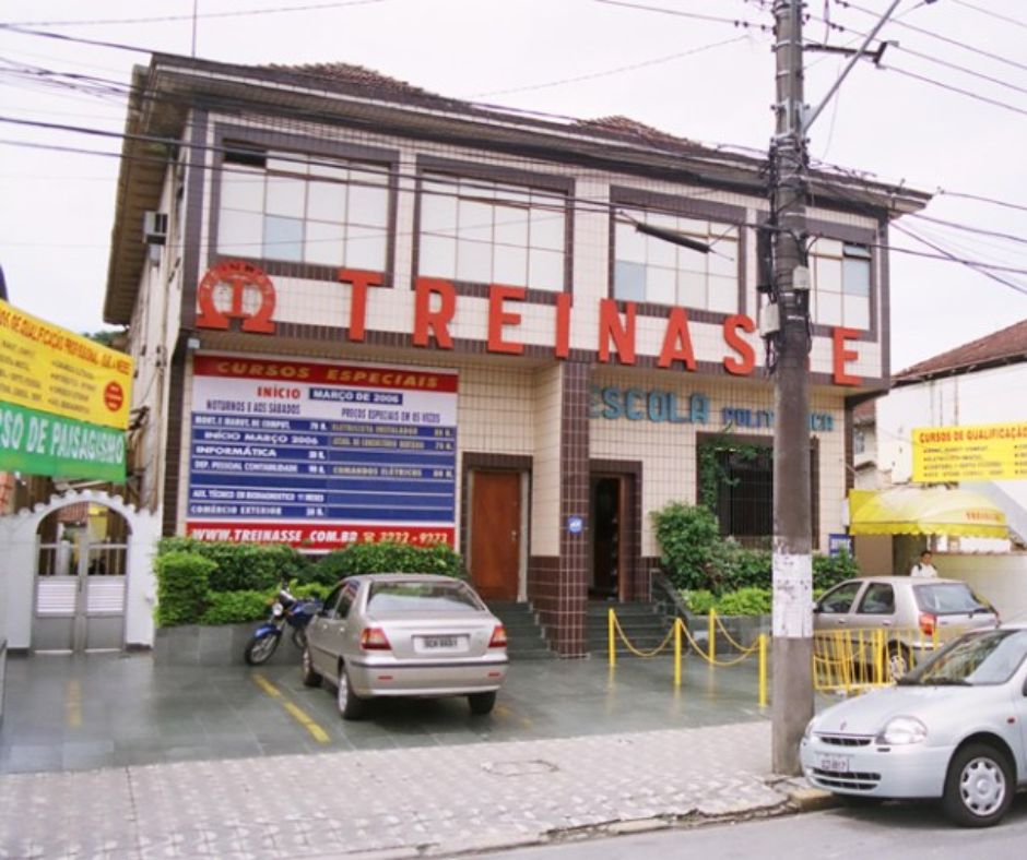 Edifício do TREINASSE com banners de cursos e estacionamento na frente