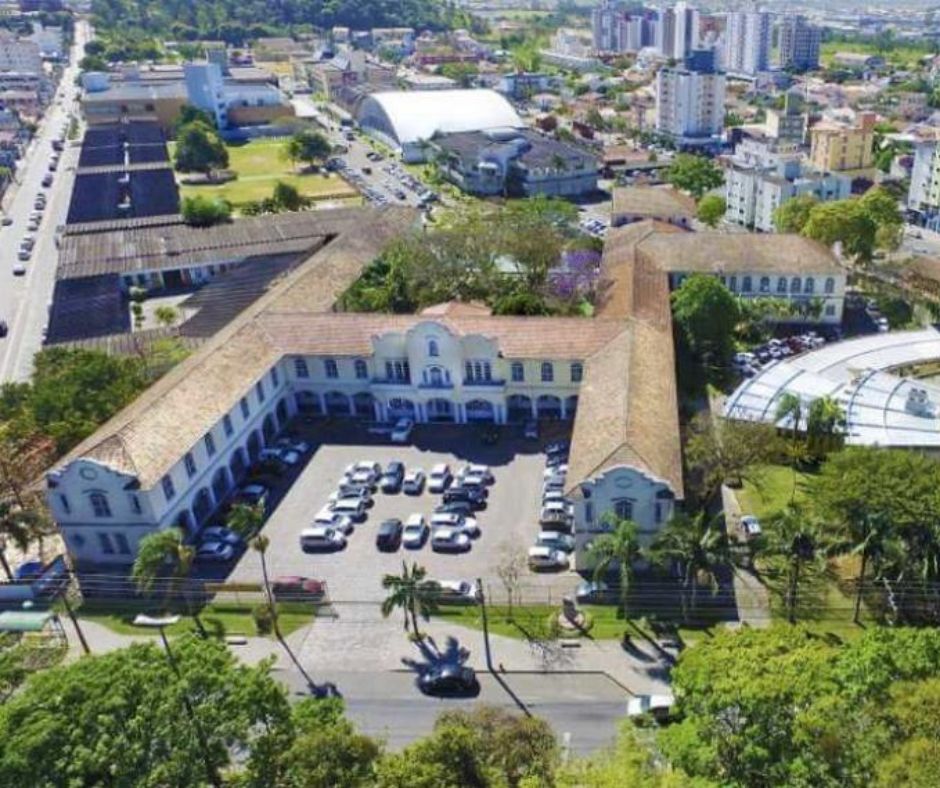 Vista aérea de um grande complexo universitário em forma de U com um pátio central