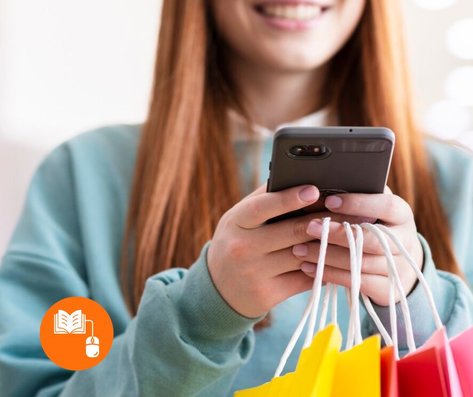 Pessoa a segurar um smartphone e vários sacos de compras com alças coloridas.