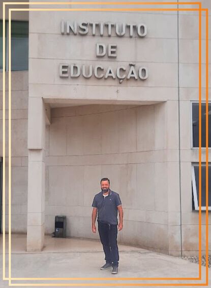Pessoa a sorrir em frente ao edifício do Instituto de Educação da Universidade de Lisboa, com fachada moderna em pedra clara